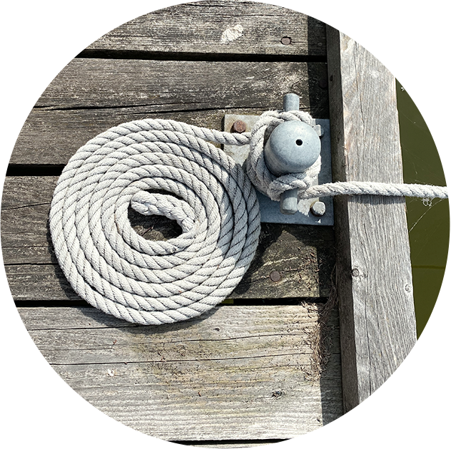 Ein zusammengerolltes Seil auf einem Steg im Wasser